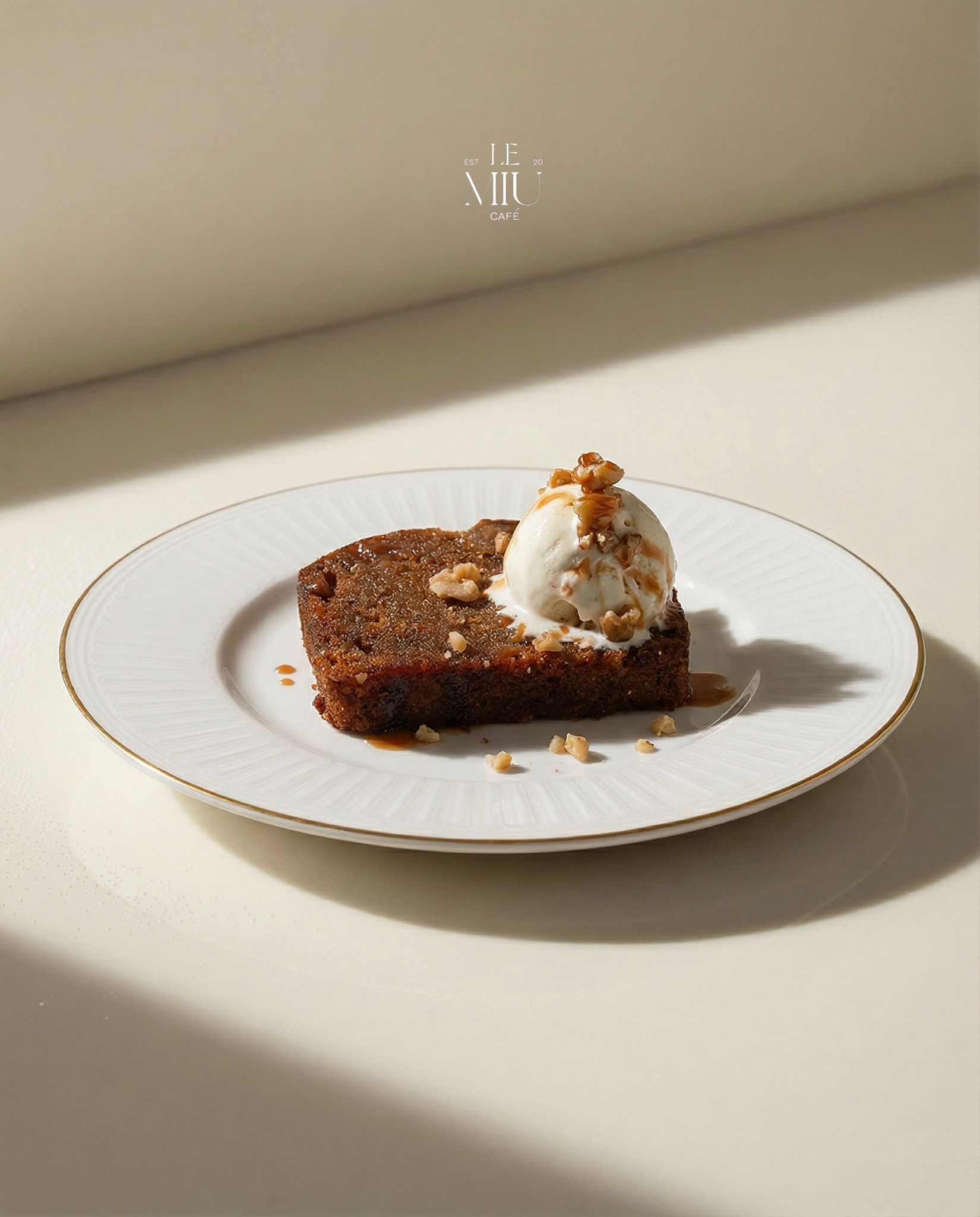 Sticky date cake with vanilla ice cream and caramel on a gold-rimmed plate